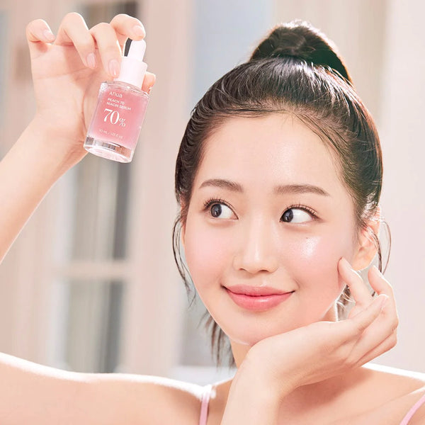 Smiling woman holding Anua Peach 70% Niacinamide Serum, illustrating the serum's use in a daily beauty routine.