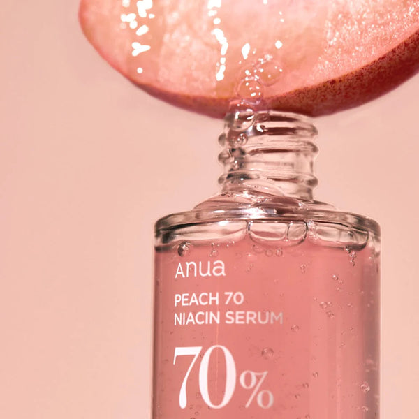 Droplet of Anua Peach 70% Niacinamide Serum falling from a sliced peach, highlighting the serum's hydrating properties.