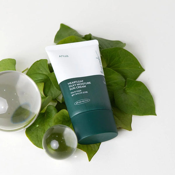 Image of Anua Heartleaf Silky Moisture Sunscreen 50ml with a backdrop of lush heartleaf plants highlighting its natural ingredients.