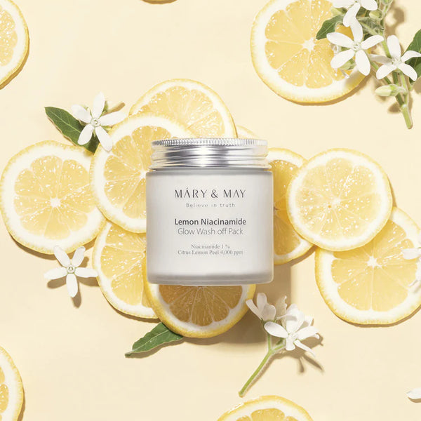 MARY & MAY Lemon Niacinamide Glow Wash Off Pack surrounded by lemon slices and white flowers, showcasing the natural citrus ingredients.
