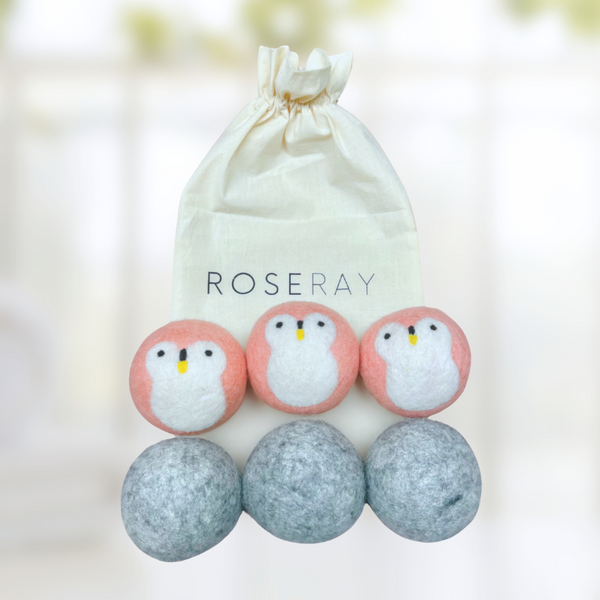 three light pink dryer balls with penguin design and three gray wool dryer balls and Roseray cotton reusable bag