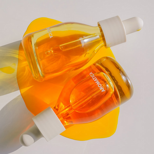 Glass bottle filled with Aromatica rose hip oil which is slightly orange