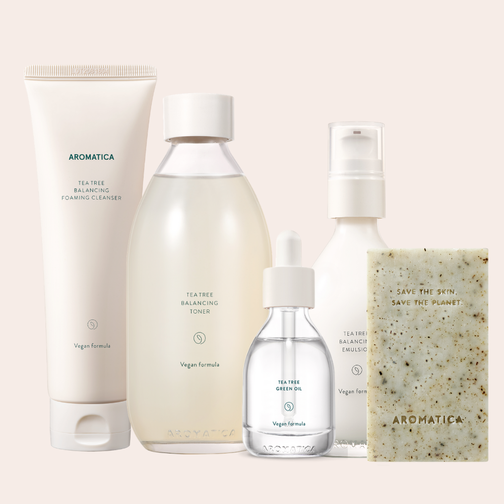 aromatica tea tree products set including a beige cleanser, beige toner in glass bottle, oil in glass bottle, and emulsion with pump in glass bottle.