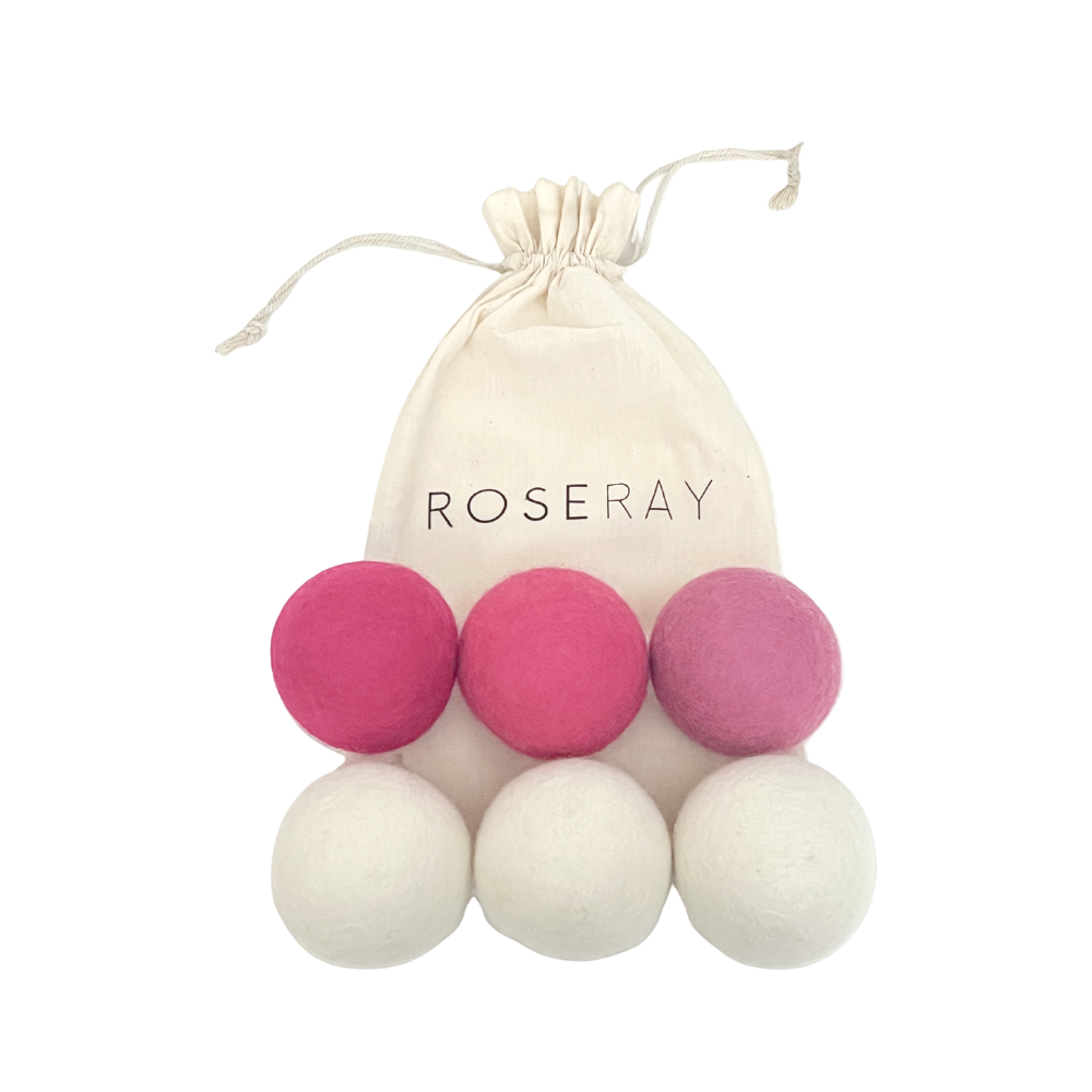 Six Roseray wool dryer balls, including three in various shades of pink and three in white, with a reusable Roseray cotton bag displayed beside them.
